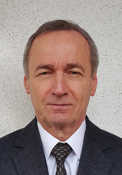 Formális öltözet, amely egy sötét zakóból, fehér ingből és mintás nyakkendőből áll.