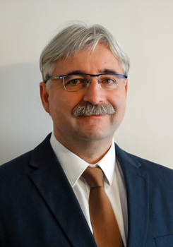 Elegáns öltönyben lévő személy, fehér inggel és barna nyakkendővel