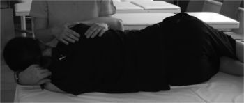 Fizioterapeuta hátkezelést végez egy fekvő páciensen, aki az oldalán fekszik.