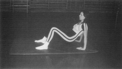 Nő tornagyakorlatot végez tornateremben Egy nő sportos ruhában tornagyakorlatot végez egy tornateremben.