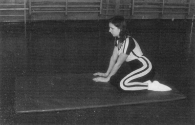 Nő tornateremben térdel egy matracon sportöltözetben Egy nő tornateremben térdel egy matracon, sportöltözetben, edzés közben.