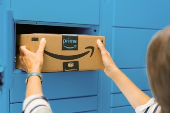 Egy személy Amazon Prime csomagot helyez el egy kék csomagmegőrző szekrényben, feliratokkal: prime, free delivery.