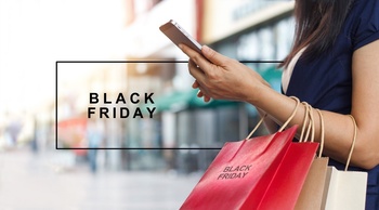 Black Friday vásárlás közben egy nő mobiltelefont használ Nő mobiltelefonnal és Black Friday feliratú bevásárlótáskákkal egy bevásárlóközpontban