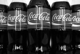 Több Coca-Cola üveg látható egymás mellett fekete-fehér képen.