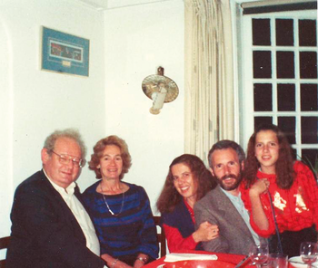 Családi vacsora az asztalnál, poharakkal és tányérokkal, háttérben ablak és falilámpa.