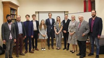 Csoportkép formális öltözetben egy beltéri rendezvényen Csoportkép, ahol emberek formális öltözetben állnak egy beltéri helyszínen, valószínűleg egy rendezvényen vagy találkozón.