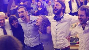 Csoportos buli tánc és ének közben Csoport ember táncol és énekel egy buliban, egymás vállát átkarolva.