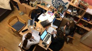 Diákok csoportban tanulnak egy asztal körül Négy diák ül egy asztal körül, laptopokkal és jegyzetekkel tanulnak egy szobában.