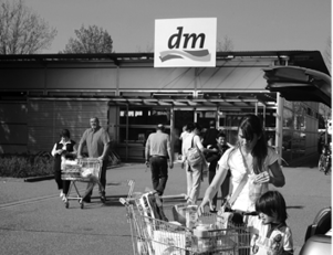 DM drogéria bejárata vásárlókkal DM drogéria bejárata, ahol emberek vásárolnak bevásárlókocsikkal.