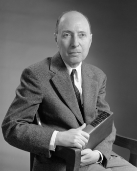 Elegánsan öltözött férfi, aki Kevin Lynch 'The Image of the City' című könyvét tartja.