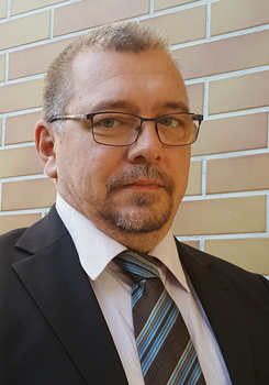 Elegáns öltönyös férfi nyakkendővel téglafal előtt