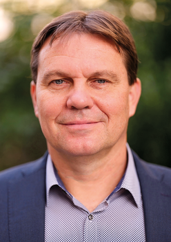 Elegáns férfi zöld háttérben Elegáns öltözetű férfi zöld növényekkel a háttérben