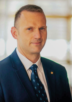 Elegáns öltönyben lévő férfi kék mintás nyakkendővel, homályosított arccal