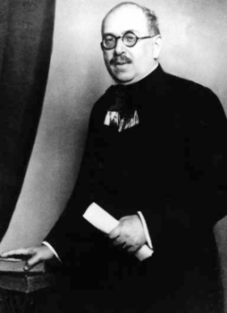 Elegáns öltözetű férfi könyvvel és papírtekercsel Elegáns öltözetű férfi könyvre támaszkodva, papírtekercset tartva.