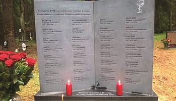 Emlékmű a sztálini terror áldozatainak, nevek és dátumok, gyertyák és virágok.