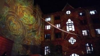 Épület fényvetítéssel éjszaka Épület falára színes, körkörös mintázatú fényvetítés van kivetítve éjszaka.