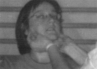 Fekete-fehér fotó csíkos fal előtt álló személlyel Fekete-fehér fotó, amelyen egy személy csíkos fal előtt áll.