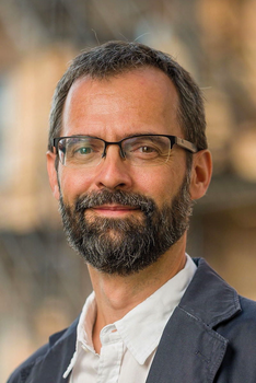 Férfi fehér ingben és sötét zakóban Férfi fehér inget és sötét zakót visel, háttér homályos.