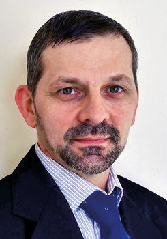 Férfi formális öltözetben, sötét öltönyben és kék nyakkendőben