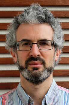 Férfi göndör, ősz hajjal és színes csíkos ingben Férfi göndör, ősz hajjal és színes csíkos ingben, fa háttér előtt