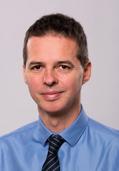 Férfi kék ingben és fekete nyakkendőben, formális öltözetben