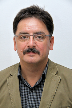 Férfi kockás ingben és világosbarna zakóban Férfi kockás ingben és világosbarna zakóban, háttérben fehér fal