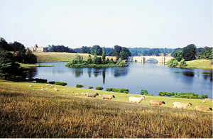 Festői táj, amely egy tóval, hídal és legelő birkákkal van körülvéve.