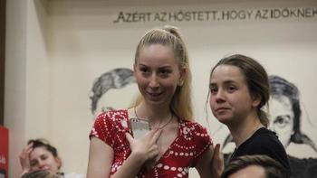 Fiatal nő okostelefonnal, felirat a háttérben Fiatal nő piros ruhában okostelefonnal, háttérben felirat és rajz