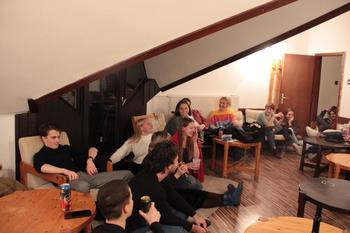 Fiatalok baráti összejövetele tetőtéri szobában Fiatalok egy tetőtéri szobában ülnek és beszélgetnek, italokat fogyasztva.