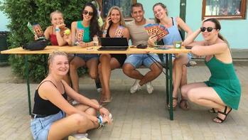 Fiatalok csoportja szórólapokkal egy asztalnál Fiatalok csoportja ül és áll egy asztal körül, kezükben szórólapokkal és egy laptop előtt.