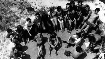 Fiatalok csoportja körben ülve egy sziklás területen, baráti társaság szabadtéri találkozója.