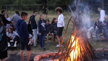 Fiatalok gyűltek össze egy tábortűz körül Fiatalok csoportja egy tábortűz körül gyűlt össze, szabadtéri kikapcsolódás.