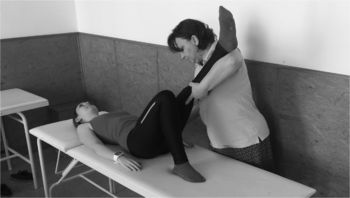 Fizikoterápiás gyakorlat, ahol egy terapeuta segít egy páciensnek a lábát nyújtani egy kezelőágyon.