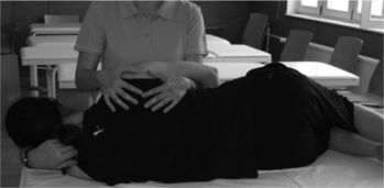 Fizioterapeuta kezeli a páciens hátát egy kezelőasztalon.