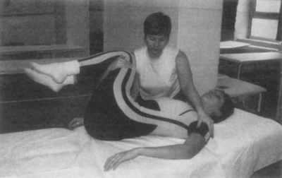 Fizioterapeuta gerinc kezelése terápiás gyakorlat során, páciens fekvő helyzetben.