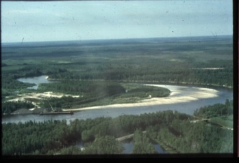 Folyó kanyarulata erdős területen Folyó kanyarulata erdős területen, körülötte zöld növényzet és táj.