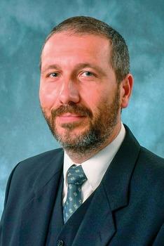 Formális öltözet kék háttérrel Formális öltözetben lévő személy kék háttérrel, öltönyben és nyakkendővel.