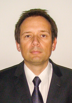 Formális öltözet, amely egy sötét öltönyből, fehér ingből és mintás nyakkendőből áll.