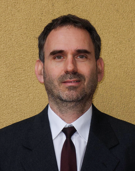 Formális öltözet sötét öltönyben, fehér inggel és bordó nyakkendővel Egy személy formális öltözetben, sötét öltönyben, fehér inggel és bordó nyakkendővel