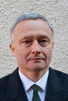 Formális öltözet sötét zakóval és zöld nyakkendővel Formális öltözet, sötét zakó, fehér ing és zöld nyakkendő textúrázott háttér előtt