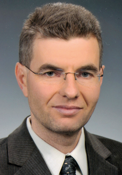 Sötét öltöny, fehér ing és mintás nyakkendő formális öltözetben.