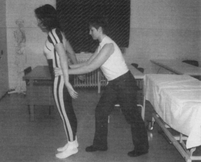 Két nő gyakorlatot végez orvosi környezetben Két nő látható, egyikük segíti a másikat egy gyakorlat végrehajtásában egy orvosi környezetben.