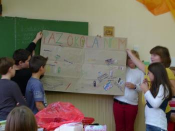 Gyerekek egy papírlapot tartanak, amelyen az 'AZ OKOLÁNOM' felirat és különböző rajzok láthatók.