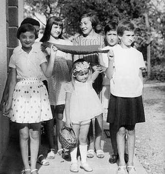 Gyerekek csoportja kígyóval vagy szalaggal Csoport gyerekek, akik egy hosszú tárgyat tartanak, fekete-fehér kép, háttérben fák.