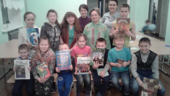 Csoportkép gyerekekről, akik különböző könyveket tartanak a kezükben egy osztályteremben.