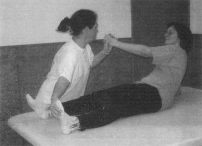 Gyógytorna gyakorlat segítése Egy nő segít egy másik személynek egy gyógytorna gyakorlat elvégzésében.