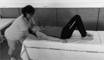 Gyógytornász segít egy páciensnek a gyakorlat végrehajtásában egy kezelőasztalon.