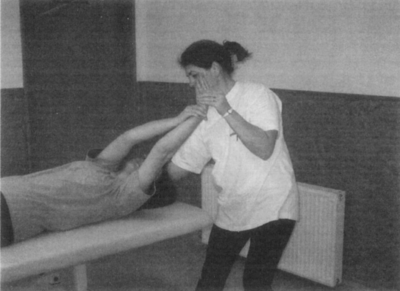 Gyógytornász nyújtja a páciens karját kezelőágyon Gyógytornász nyújtja a páciens karját, aki egy kezelőágyon fekszik.