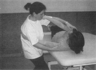 Gyógytornász segít páciensnek a kezelőágyon Gyógytornász segít egy páciensnek a gyógytorna gyakorlatok végrehajtásában egy kezelőágyon.