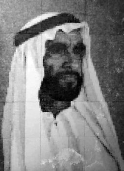 Hagyományos arab viselet, fehér ruha és fekete-fehér fejfedő látható.